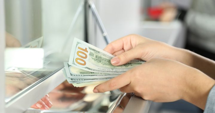 Kobieta w kantorze trzyma w dłoni pieniądze