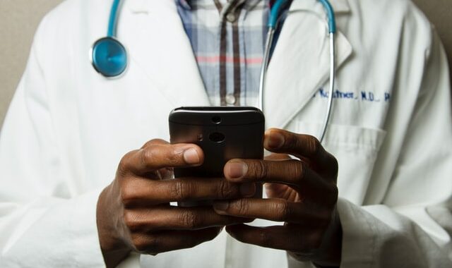 Lekarz z telefonem w ręce sprawdza wizyty swoich pacjętów